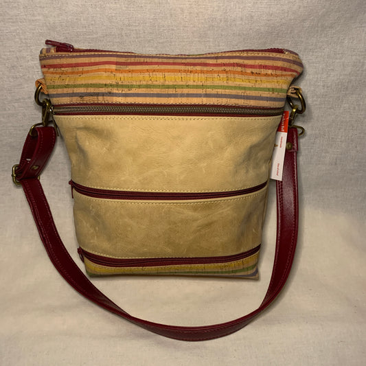 Mixed media crossbody bag of leather and cork with multiple exterior zipper pockets.