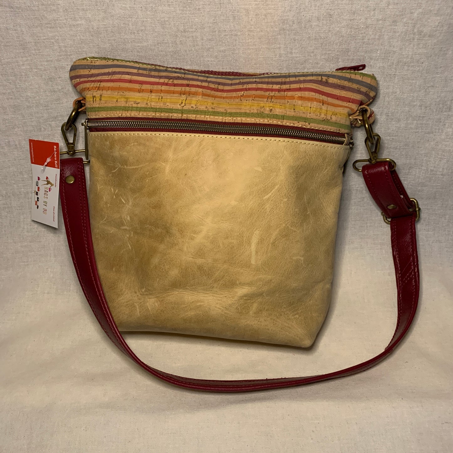 Mixed media crossbody bag of leather and cork with multiple exterior zipper pockets.