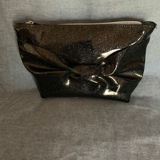 Sparkling black vinyl pouch with front bow and top zipper.