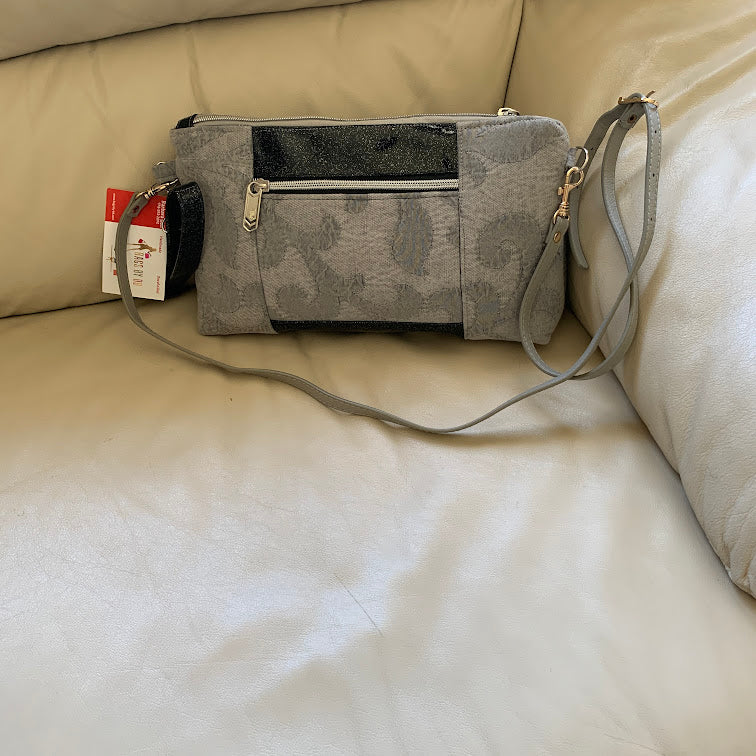 Gray and black crossbody bag with adjustable strap and wristlet strap.